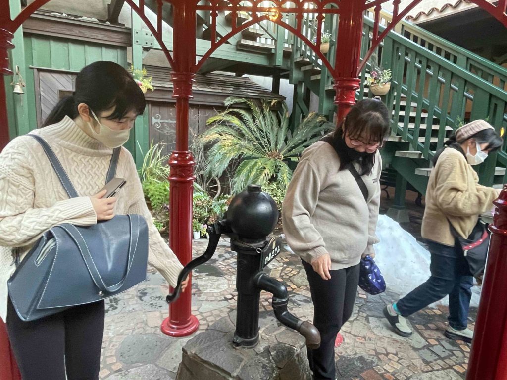 手こぎポンプを眺める雨宮さんと中村さん。中村さんとが手こぎポンプに触れている。